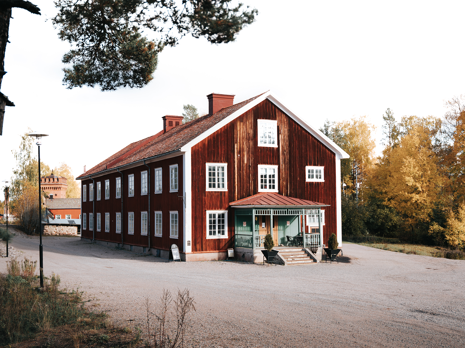 Historic red wooden building with white trim and green entryway, surrounded by autumn foliage at Sala Silvergruva.